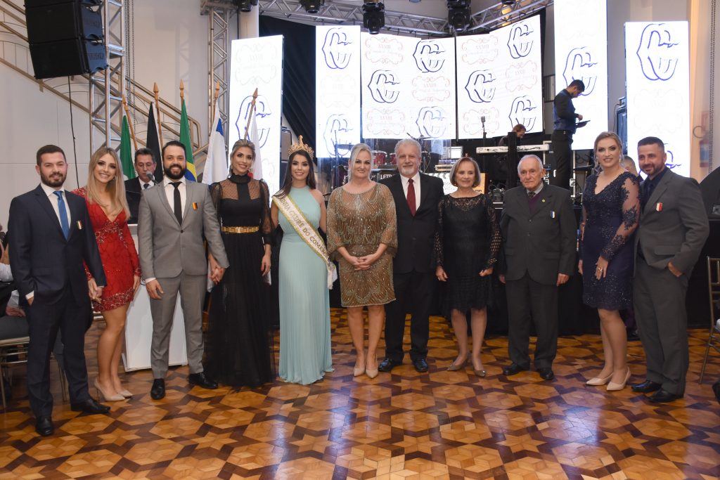 No centro, a presidente do CC, Katiamara Badalotti e o esposo, Luís Badalotti, a Rainha  e os casais da 33ª Comenda do Imigrante   |   Crédito: André Fotos